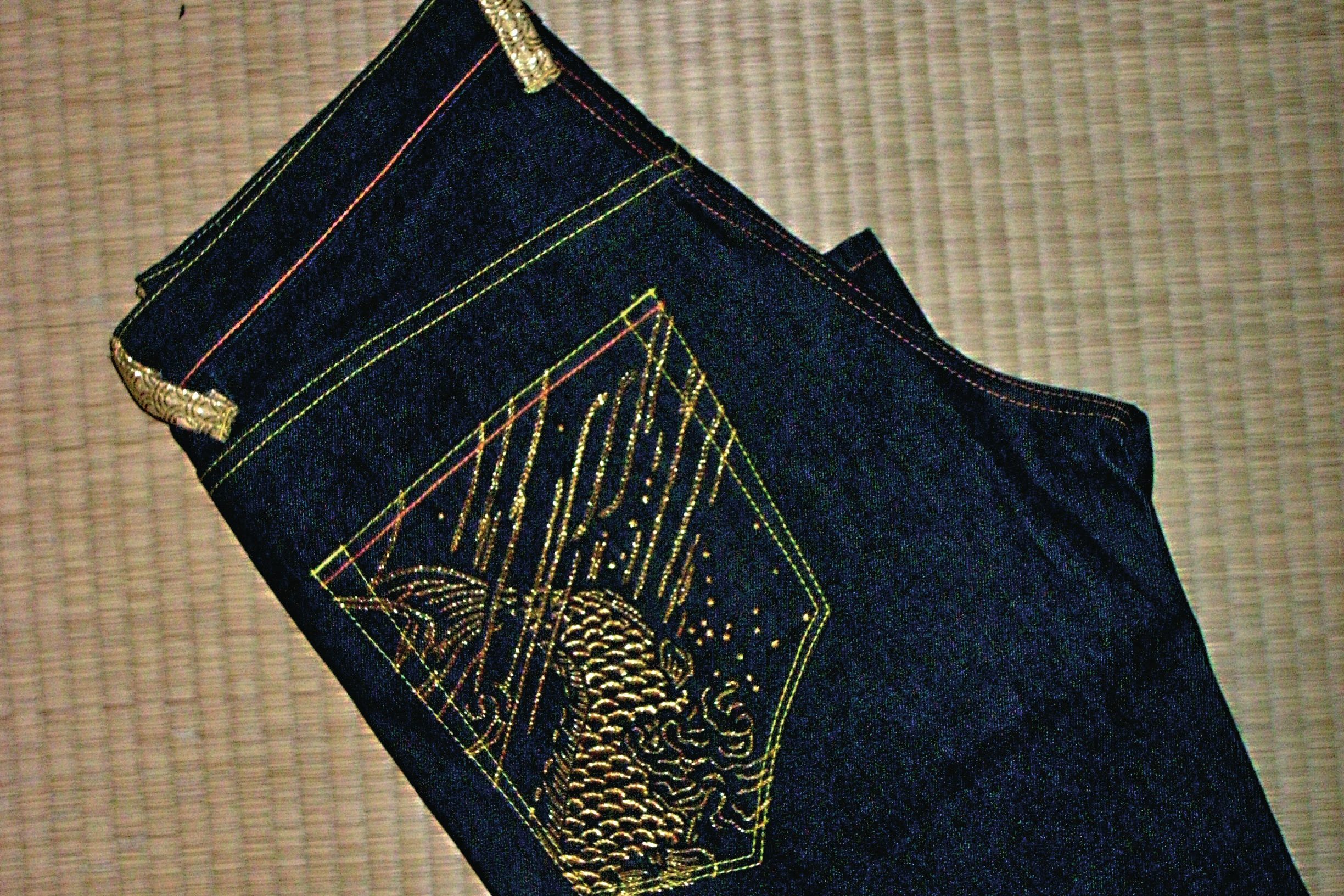 Folded pair of The Year of… jeans with gold-embroidered pocket